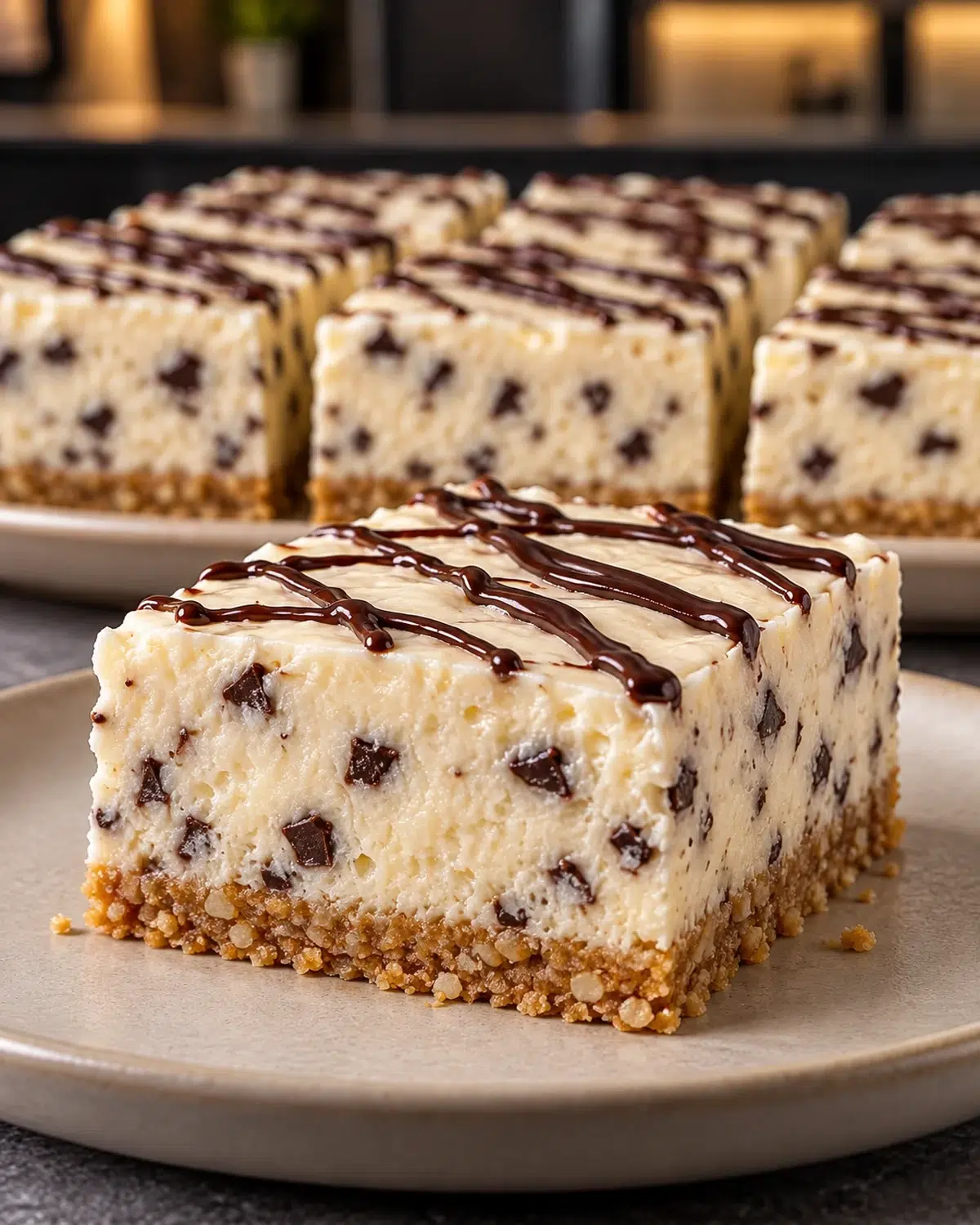 Sugar-free chocolate chip cheesecake bars on a plate with chocolate drizzle