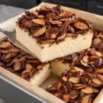 Sugar-free chocolate crunch cheesecake bar with chocolate almond clusters lifted from a square pan