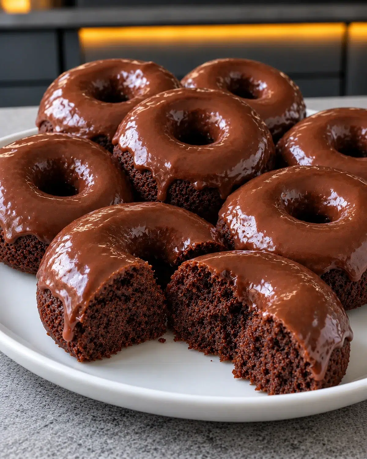 Sugar-free chocolate donuts with glossy chocolate glaze on a white plate, one broken open