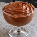 Sugar-free chocolate protein pudding with a glossy swirled top in a clear footed glass coupe