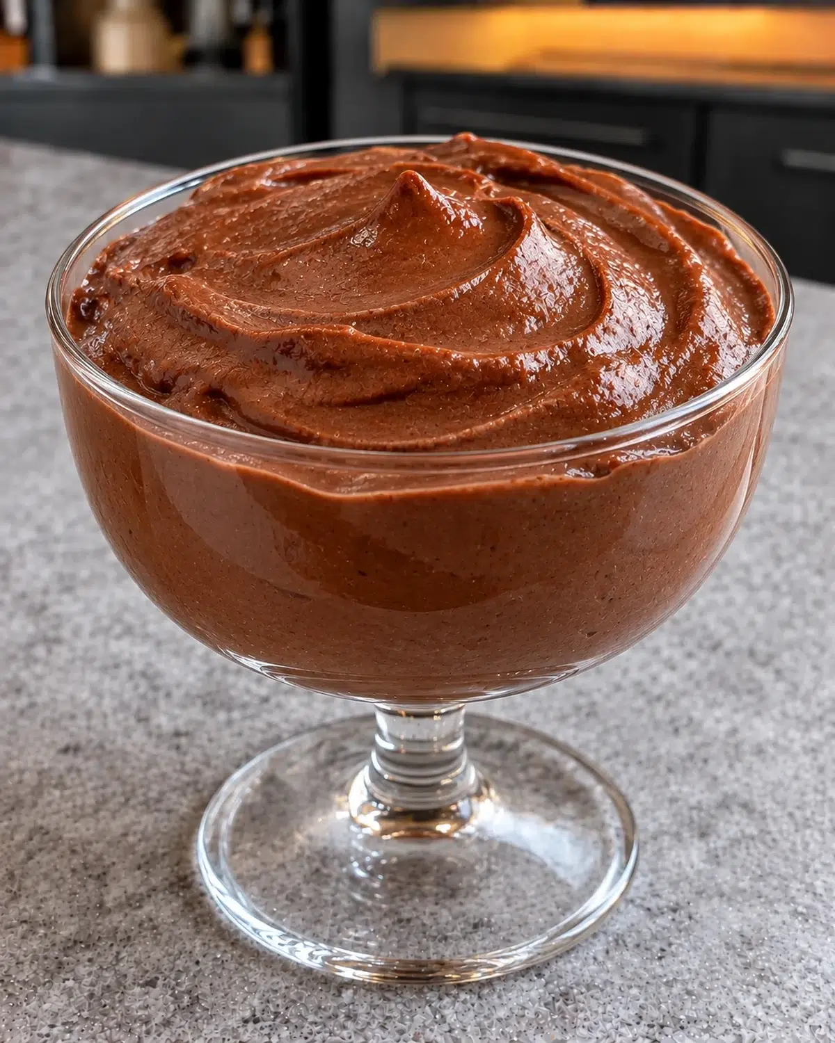 Sugar-free chocolate protein pudding with a glossy swirled top in a clear footed glass coupe