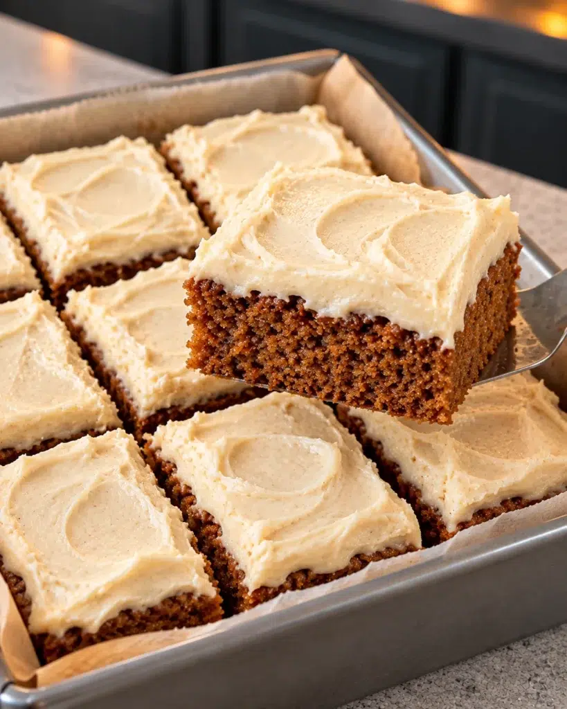 Sugar-free gingerbread bars with thick cream cheese frosting, one square lifted from the pan